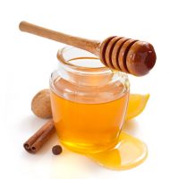 glass jar of honey and dipper isolated on white background